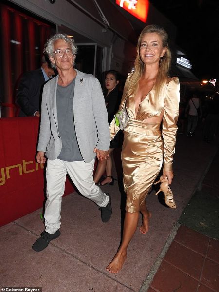 Paulina Porizkova in a golden dress poses with boyfriend Ed Solomon